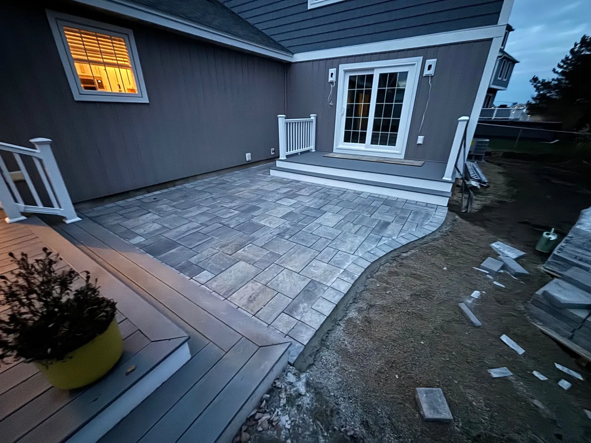 Paver patio installed beside a house and deck